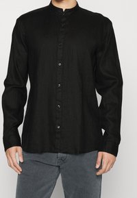 Camicia nera a maniche lunghe in lino con colletto alla cinese, con bottoni neri e vestibilità comoda. Tessuto con texture e leggero lucido.