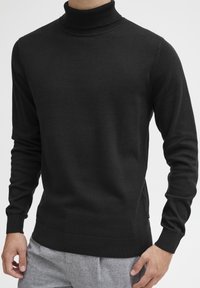 Maglione dolcevita nero in morbido tessuto, con maniche lunghe, polsini e colletto a coste, e una vestibilità aderente. Si abbina bene a vari stili.