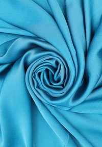 Tessuto ciano, morbido e liscio, disposto a spirale. La trama è leggermente lucida con una sottile lucentezza, che mostra un colore solido senza motivi.