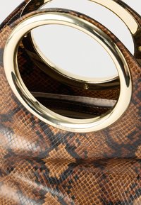 Καφέ τσάντα με μοτίβο δέρματος φιδιού και χρυστές οβάλ λαβές, που εμφανίζει εσωτερική τσέπη με φερμουάρ.