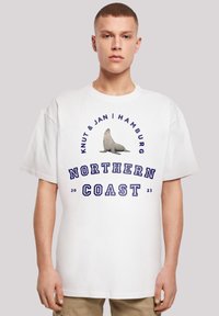 Weißes Baumwoll-T-Shirt mit einem Seehund-Design und dem Text "Knut & Jan | Hamburg", "NORTHERN COAST" und dem Jahr "2023" in Blau.
