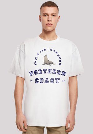 White cotton t-shirt featuring a seal graphic and text "Knut & Jan | Hamburg", "NORTHERN COAST", and year "2023" in blue.