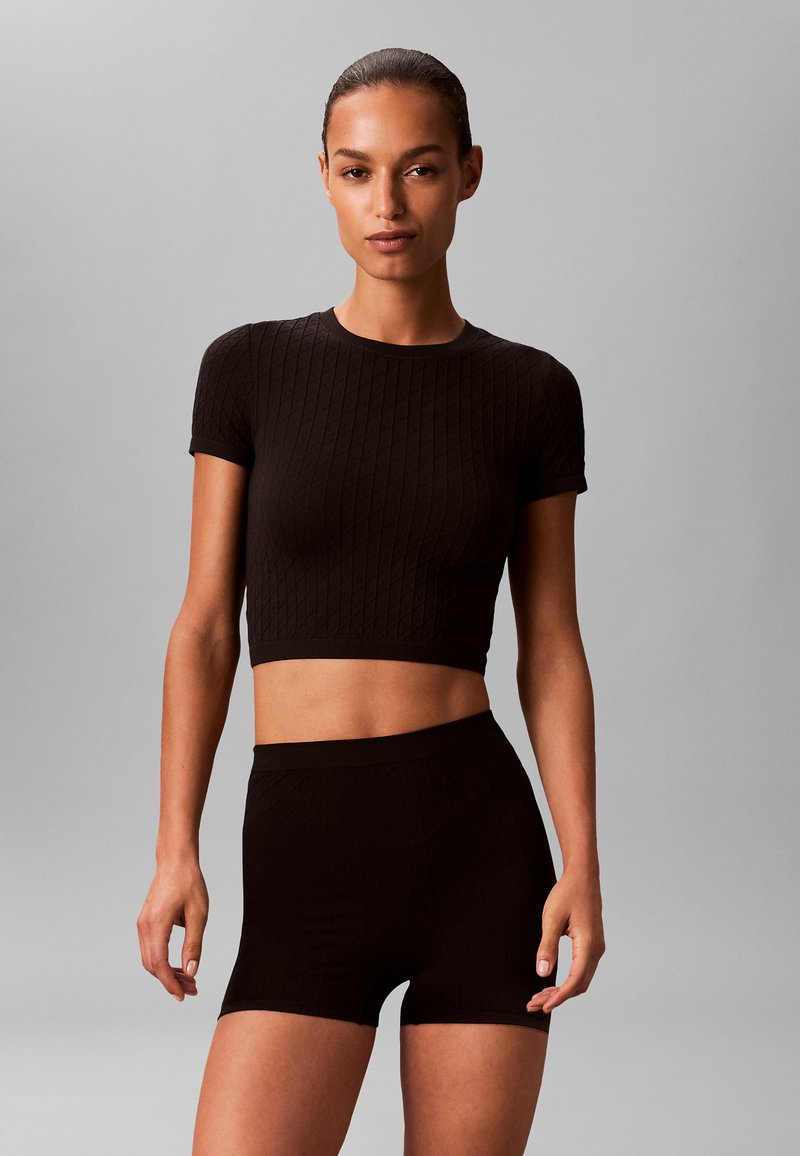 Zwart geribd cropped top en korte broekset met een gestructureerd patroon en aansluitend ontwerp, gemaakt van rekbaar, zacht materiaal. Geschikt voor sportieve activiteiten.