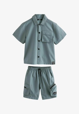 Hele roheline lühikeste varrukatega särk nupuga ja taskuga, millest koosnevad sobivad lühikesed püksid elastse vöökohaga ja küljetaskuga.