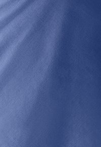 Tissu bleu lisse avec une texture de tissage fine et des plis doux visibles sur toute la surface.