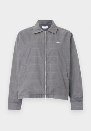 Pilka užtraukiama striukė su subtiliu mėlyno langelio raštu, apykakle, šoninėmis kišenėmis ir mažu balto "obey" logotipu krūtinės srityje.