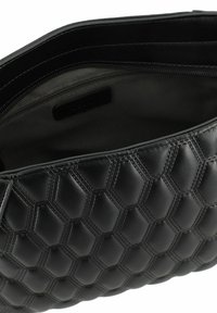 Black leather handbag featuring a hexagonal quilted pattern, smooth texture, and a zippered compartment. Interior is lined and dark.