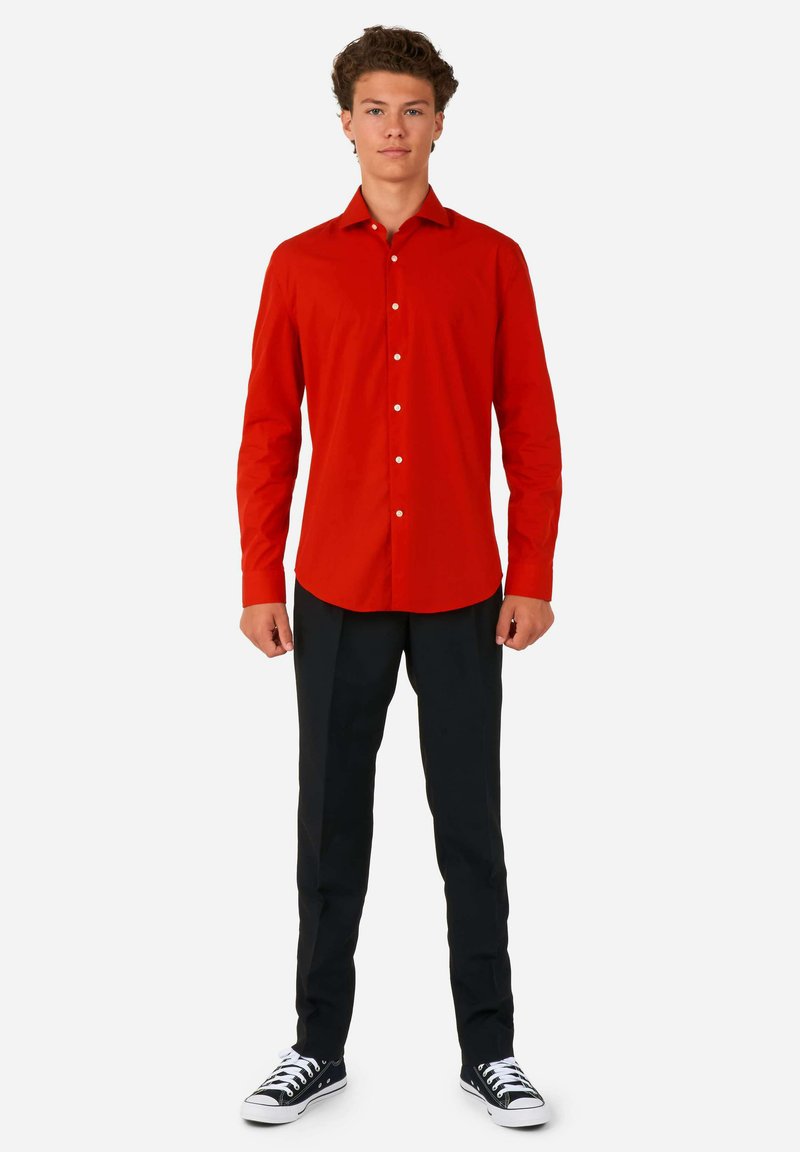 Rode langslavenshirt met een knoopsluiting, gecombineerd met zwarte broek en zwarte sneakers. Het shirt heeft een zachte textuur en witte knopen.