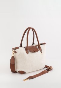 Bolso de piel de oveja con detalles en cuero marrón, asas dobles y una correa desmontable. Cuenta con herrajes dorados y una forma estructurada.