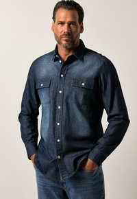 Camisa de mezclilla azul oscuro, estilo de botones, con dos bolsillos en el pecho con solapa, un degradado de azul más claro en contraste y mangas largas.