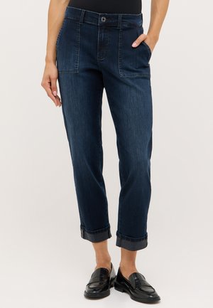 Pantalons en denim foncé à coupe décontractée, dotés de poches frontales et de bords roulés. Le tissu a une texture lisse et un design classique.