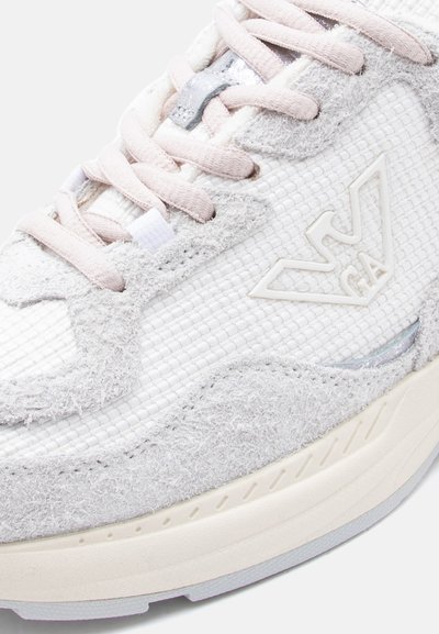 Λευκό και ανοιχτόγριζο αθλητικό παπούτσι με υφή, με απαλό ροζ κορδόνια και ανάγλυφο λογότυπο σε σχήμα V στη πλ ευρά.