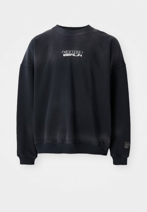 Black sweatshirt made of cotton blend, featuring ribbed cuffs and neckline. Front has white text "CATERED BERLIN" in stylized font.