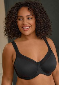 Soutien-gorge noir en tissu lisse avec un design structuré. Présente des bretelles larges, une superposition en mesh et des coutures verticales pour le soutien et la forme.