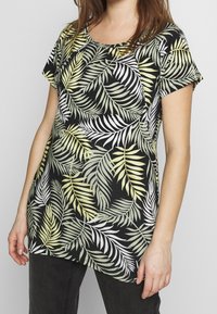 Černý krátký rukáv top s listovým zeleným a bílým potiskem palmy. Vyrobeno z měkké látky, s volným střihem a kulatým výstřihem.