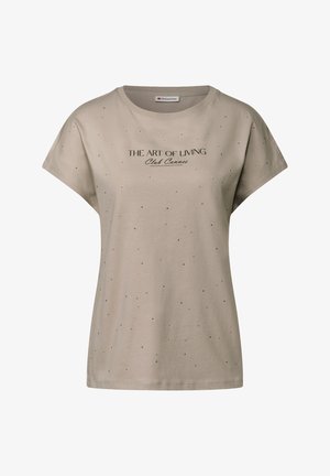 Beige kortærmet t-shirt med rund hals, prydet med sort tekst "THE ART OF LIVING Club Cannes" og spredte sorte prikker til dekoration.