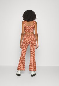 Conjunto de duas peças com padrão zigzag vermelho e branco, composto por um top cropped e calças largas, feito de um tecido de textura suave.