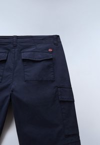 Merivoimien cargo-housut, joissa on kaksi suurta sivutaskua, pieni kirjailtu lipputunnus ja sileä kangaspinta.