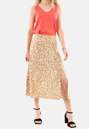 Top sin mangas de pico color coral combinado con una falda maxi de estampado de leopardo beige que presenta una gran abertura. La modelo lleva unos tacones negros de tiras.