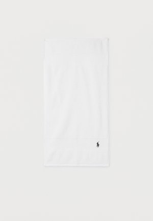 Serviette à main en coton blanc avec un petit logo de joueur de polo noir brodé près du bord inférieur.