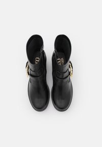 Botines de cuero negro hasta el tobillo con punta redonda, cremalleras laterales y un acento de hardware dorado. Textura suave con una suela flexible.