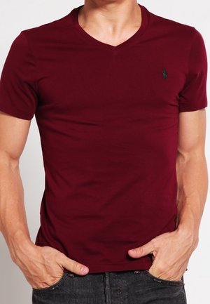 T-shirt bordeaux à manches courtes et col en V, en coton doux, avec un petit logo vert sur la poitrine gauche et une coupe ajustée.