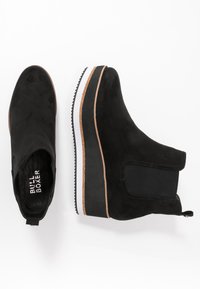 Czarne zamszowe botki za kostkę z platformą. Posiadają elastyczne panele boczne, okrągły czubek i teksturowaną gumową podeszwę.