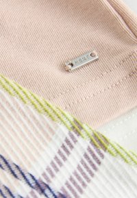 Pink ribbed fabric with a silver "NEXT" tag. A patterned section features stripes in purple, blue, and green colors.