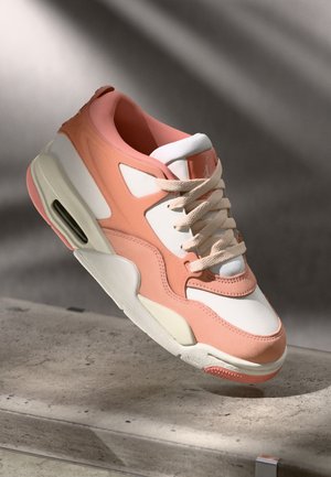 Baskets avec un dessus rose pâle et blanc, un revêtement en suede texturé, un col rembourré et une unité d'air visible au niveau du talon. Semelle couleur crème.