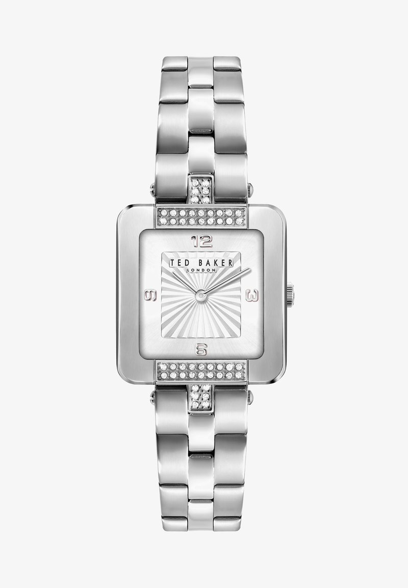 Sudraba metāla pulkstenis ar kvadrātu formas seju, teksturētu balto ciparnīcu, paceltām stundu atzīmēm un kristāla akcentiem siksniņā un korpusā.