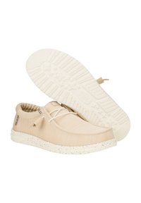 Beige Netzschuhe mit einer strukturierten Oberfläche und einer gesprenkelten weißen Sohle. Merkmale sind eine abgerundete Zehenpartie und ein einfaches Schnürdesign.