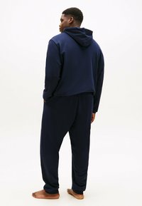 Granatowa bluza z kapturem o luźnym kroju, z kapturem i długimi rękawami, zestawiona z pasującymi dresami. Miękka, gładka tkanina, casualowy design.