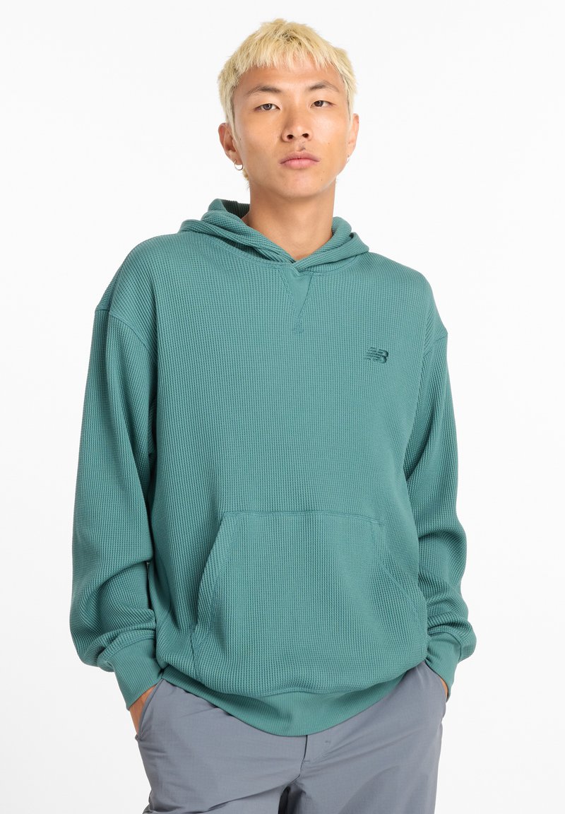 Sudadera con capucha de punto verde con un bolsillo frontal, corte relajado y capucha con cordón. Presenta un pequeño logo en el pecho. Hecha de tela texturizada.