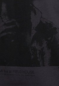 Schwarzes T-Shirt aus Stoff mit einem grafischen Druck einer Person und Laub. Der Text ist in einer kontrastierenden Farbe nahe dem unteren Rand gedruckt.