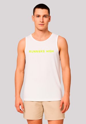 Man wearing white sleeveless shirt with yellow "RUNNERS HIGH" text and beige shorts, standing against light gray background.