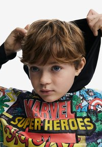 Huppari, jossa on värikäs Marvel-superhero-tulostus, monivärinen kangas ja musta huppu. Pehmeä rakenne ja elävät yksityiskohdat ovat näkyvissä.