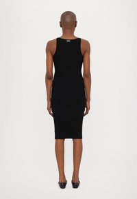 Rochie din material elastic, neagră, cu o croială slim, de lungime până la genunchi, cu un mic eticheta în zona gâtului pe spate. Textură netedă, fără mâneci.