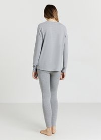 Haut à manches longues en coton gris et leggings, avec une coupe décontractée et une texture lisse. Aucune motif ou accent visible.