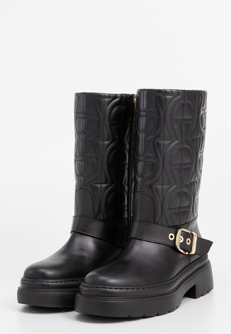 Schwarze Leder-Stiefeletten mit gestepptem Muster, goldener Schnallenakzent und dicker Plateausohle. Seitlicher Reißverschluss für ein einfaches An- und Ausziehen.