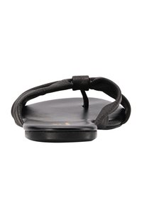 Sandalo in pelle nera con suola piatta, design aperto e sottili cinghie intrecciate. Presenta un anello tra le dita dei piedi e hardware minimal.