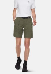 Olivgröna shorts med flera fickor, tillverkade av lättviktigt tyg. Matchas med en vit t-shirt och svarta vandringsskor.