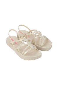 Sandali beige con più cinturini, suola testurizzata e suola spessa. Include un dettaglio di marca rosa sul lato interno.