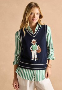 Tumes sinine kudumvest valge äärisega, millel on spordiriietuses rebane. Roheline ja valge triibuline särgialus. Lõdva stiiliga, sobib kihistamiseks.