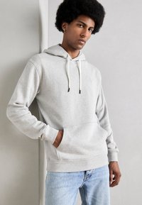 Lichtgrijze hoodie van een zachte katoenmix, voorzien van een trekkoordcapuchon, een voorzak met kangaroo-pocket en ribgebreide mouwen. Inclusief een minimalistisch ontwerp accent.