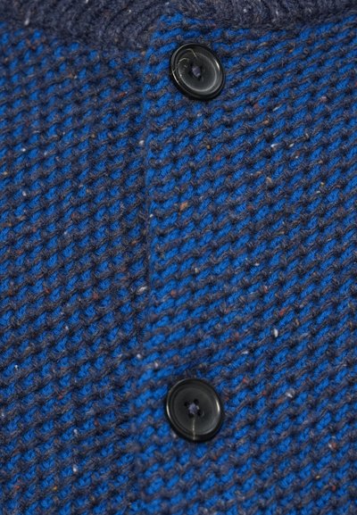 Marineblaue und blaue Strickstoff mit strukturiertem Muster, versehen mit zwei schwarzen Knöpfen und einem gerippten Kragen.