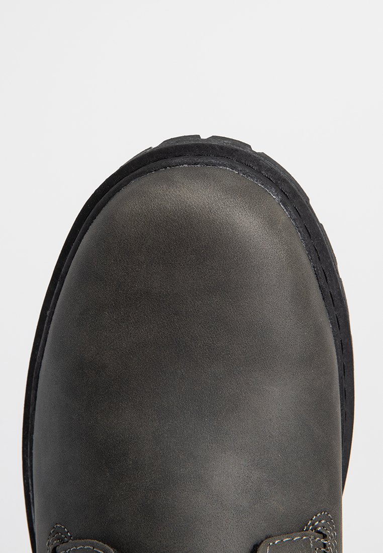 Zbliżenie na solidny czarny skórzany czubek buta z grubą gumową podeszwą i widocznymi detalami szewnymi.