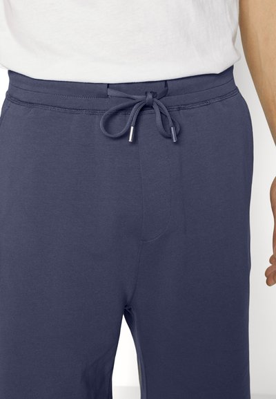 Calças de jogging azul-marinho feitas de um tecido suave e leve. Apresenta uma cintura elástica com cordão e bolsos laterais.