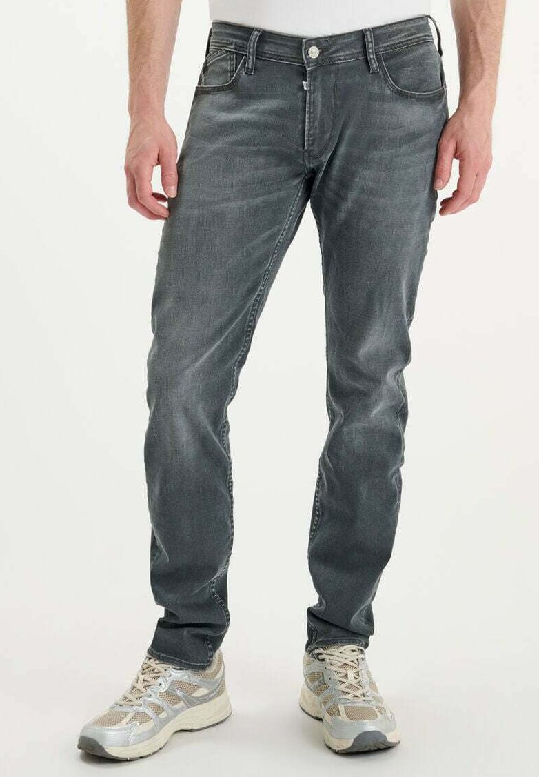 Jeans in denim grigio con una vestibilità slim, cinque tasche e un leggero effetto sbiadito. Abbinati a scarpe da ginnastica grigio chiaro con dettagli in rete.