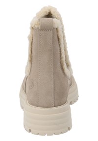 Beige suède enkellaars met nepbontvoering bij de kraag, solide rubberen zool en een reliëflogo op de achterkant.