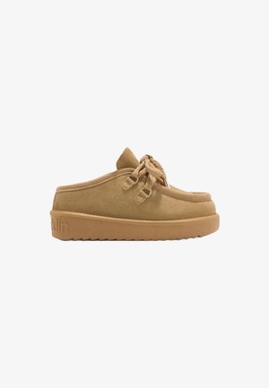 Zapato de ante color marrón claro, estilo mocasín, con suela de goma gruesa, cordones en la parte delantera y logotipo grabado en el talón.